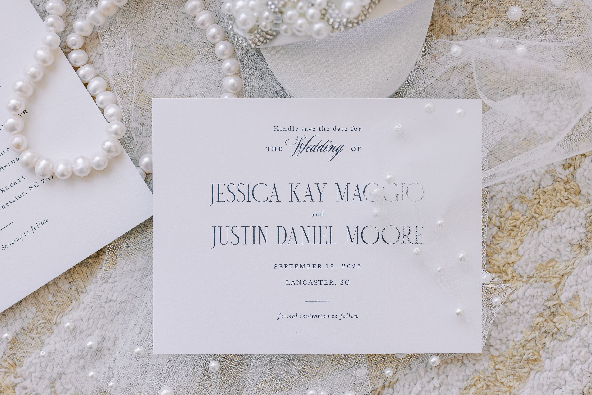 Wedding invitation suite with elegant typography laid out on a textured white and gold surface.
