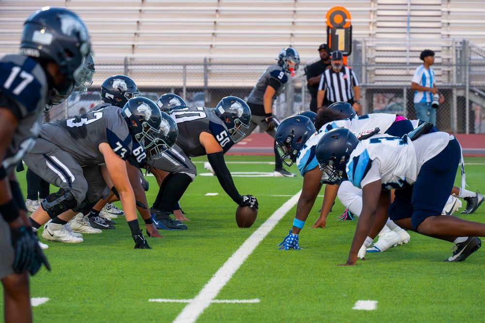 Two football teams line up at the line of scrimmage during a high school football game.