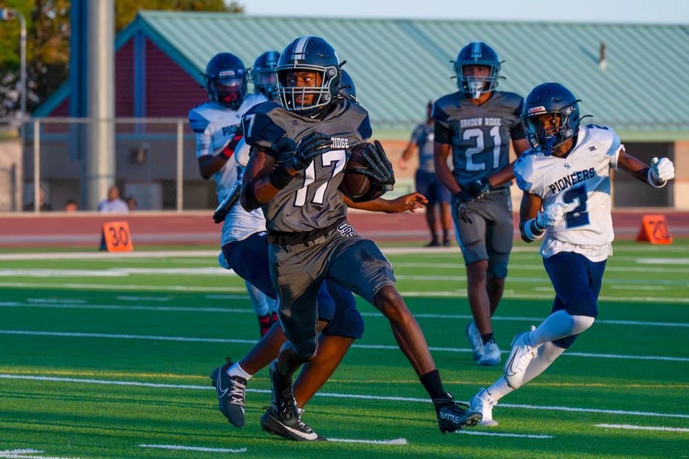 Number 17 in gray uniform outruns Pioneers defenders while carrying the football downfield.