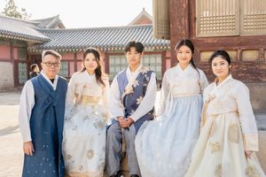 People in traditional Korean hanbok attire walking through a palace courtyard.