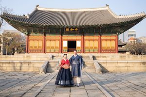 Traditional Korean palace buildings with curved roofs against blue sky.