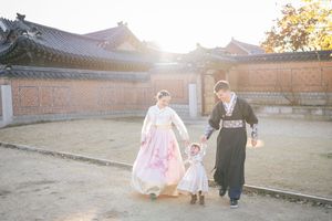 Traditional Korean palace courtyard with ornate architecture and stone walkways at sunset.