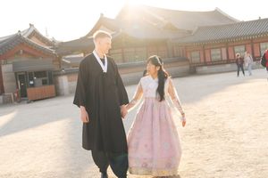 Groups gathered in traditional Korean formal wear at a historic palace during golden hour.
