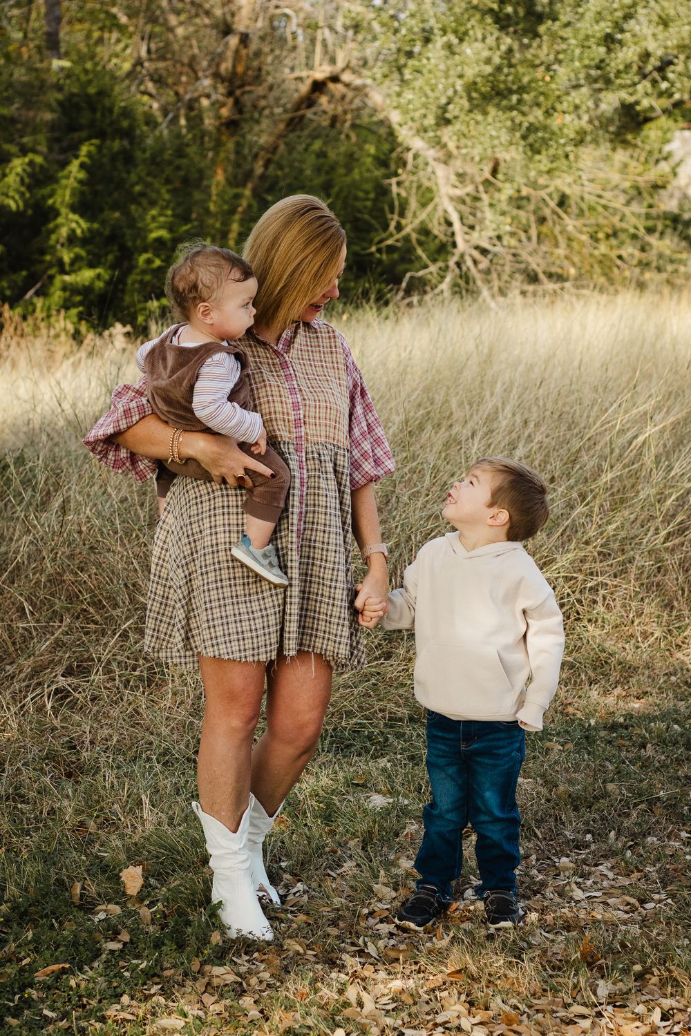 An outdoor family portrait in a field with coordinated casual fall outfits.