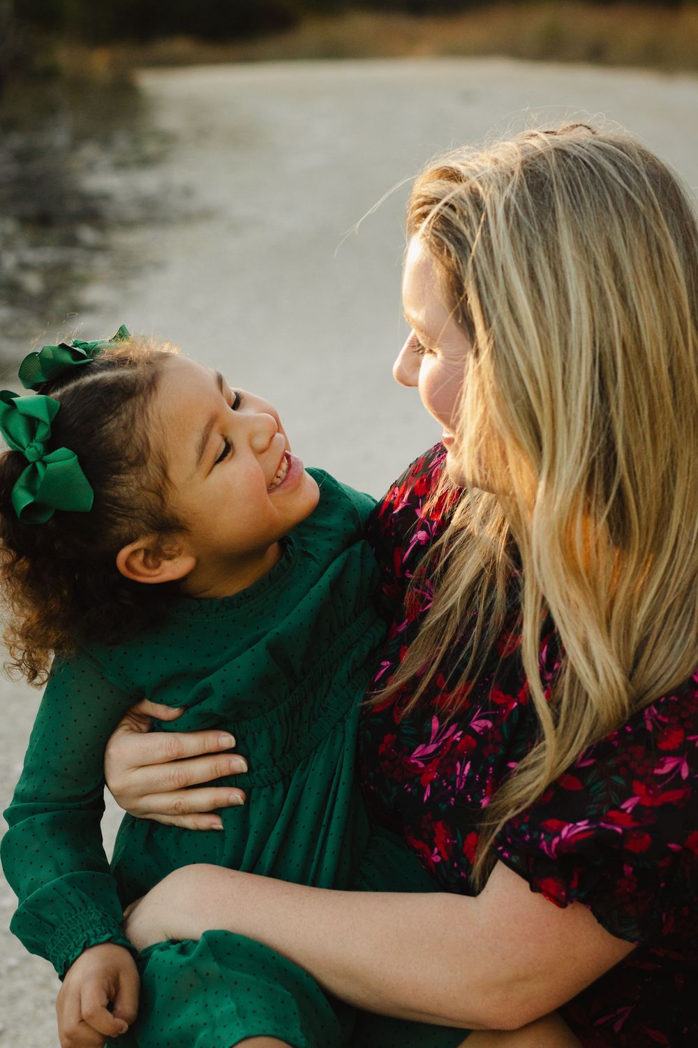 A heartwarming moment of laughter and connection between a young child in green and an adult outdoors at sunset.