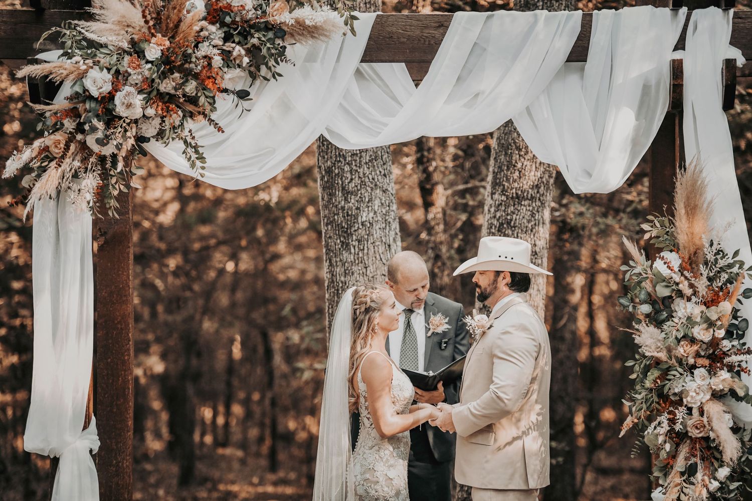 Bride and groom exchanging vows under the altar framed with greenery and floating candles taken by april pinto photography
