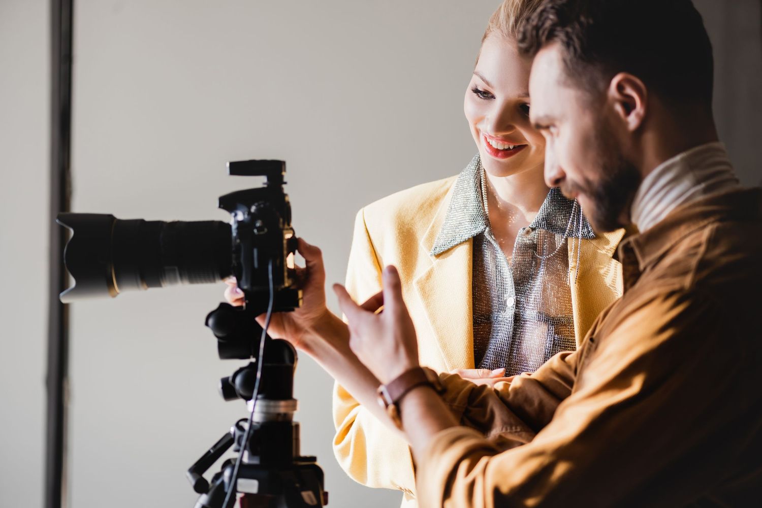 Photographer adjusts settings on professional camera in bright window light.