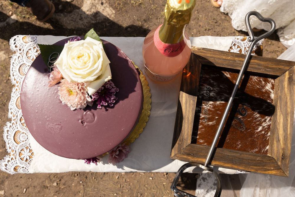 Purple and pink glazed cakes with delicate floral decorations and lace details sit on display plates.