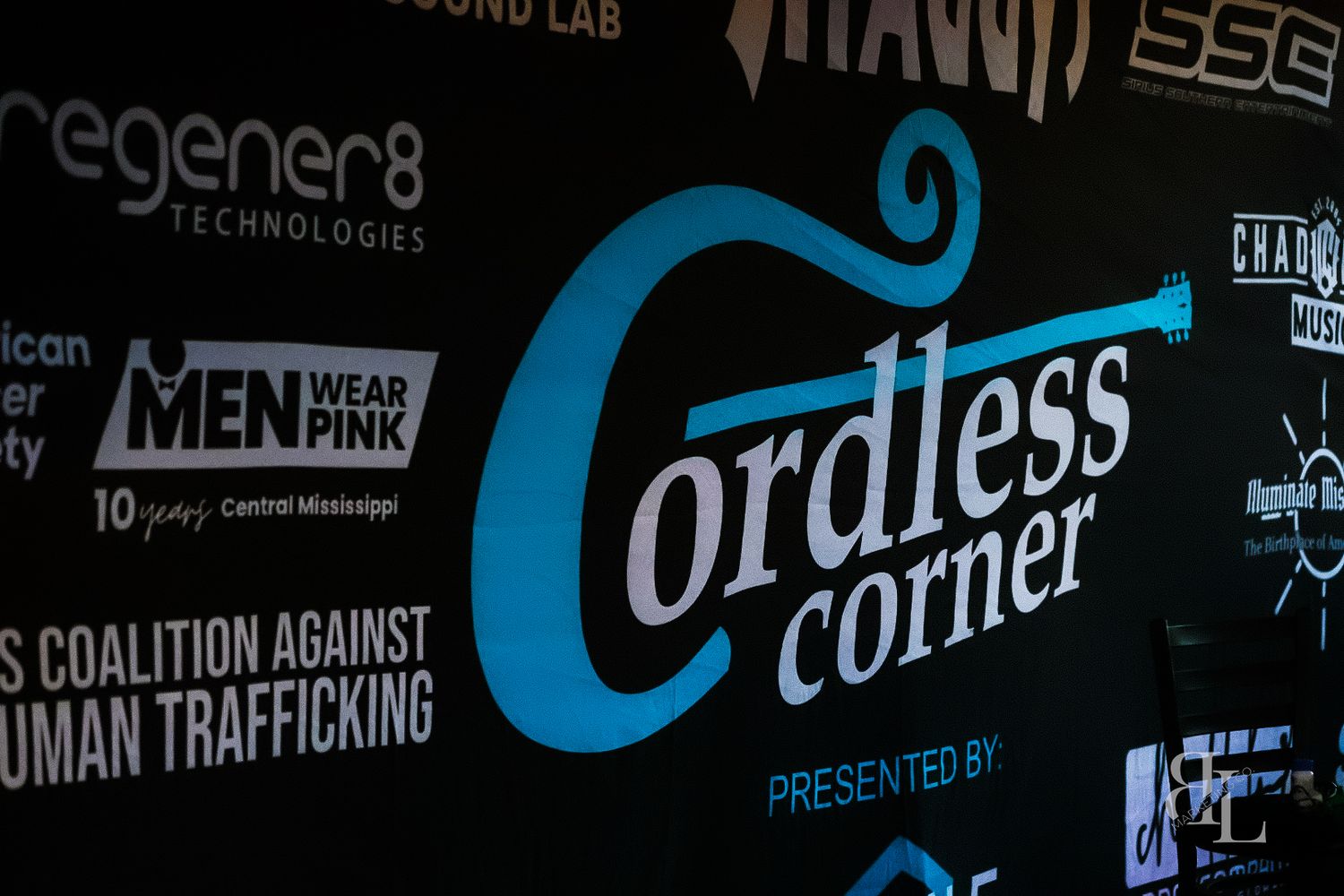 Digital sign or screen display showing various business logos and text in black and blue colors against a dark background.