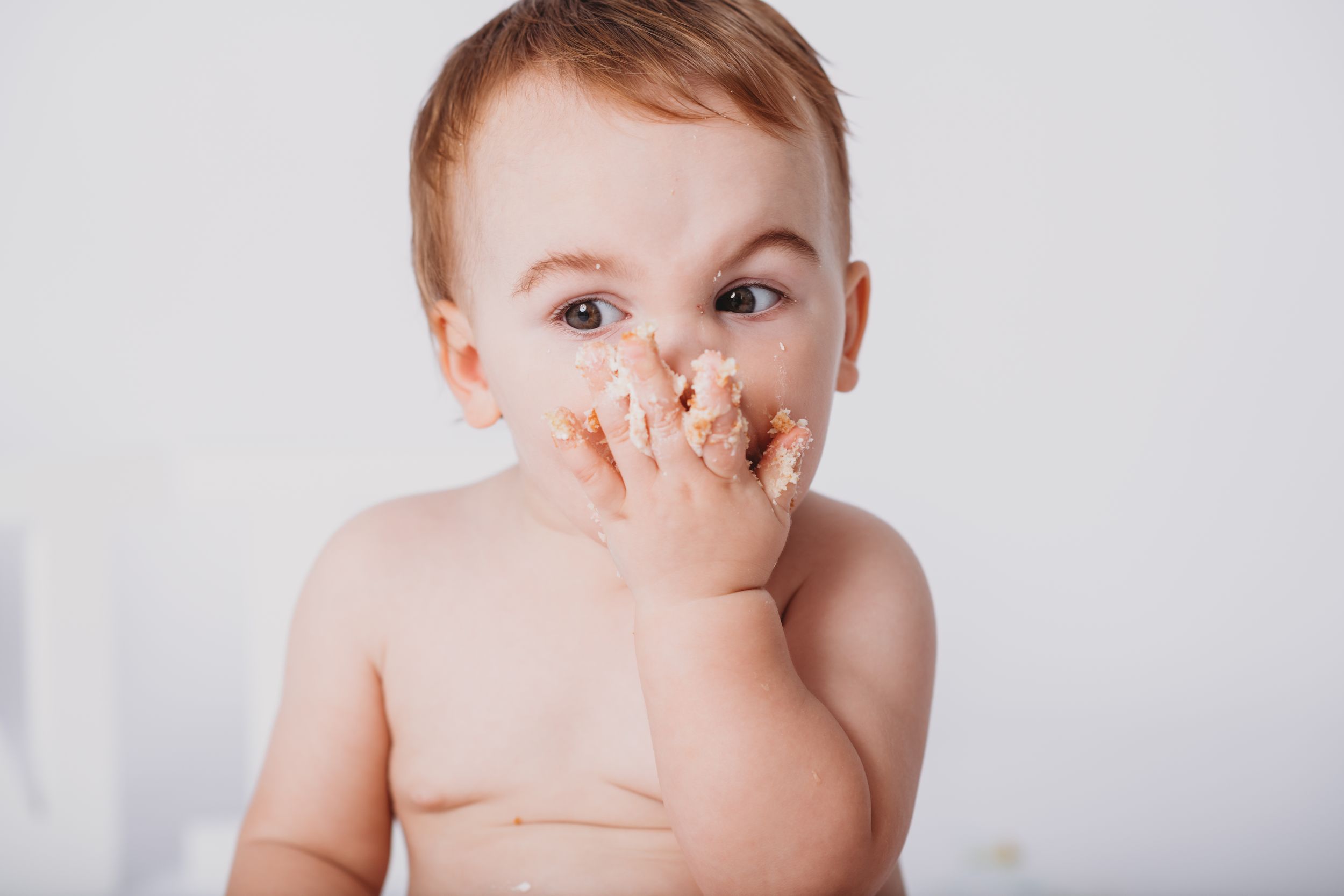 Close up portrait of baby with messy face during cake smash photo session.