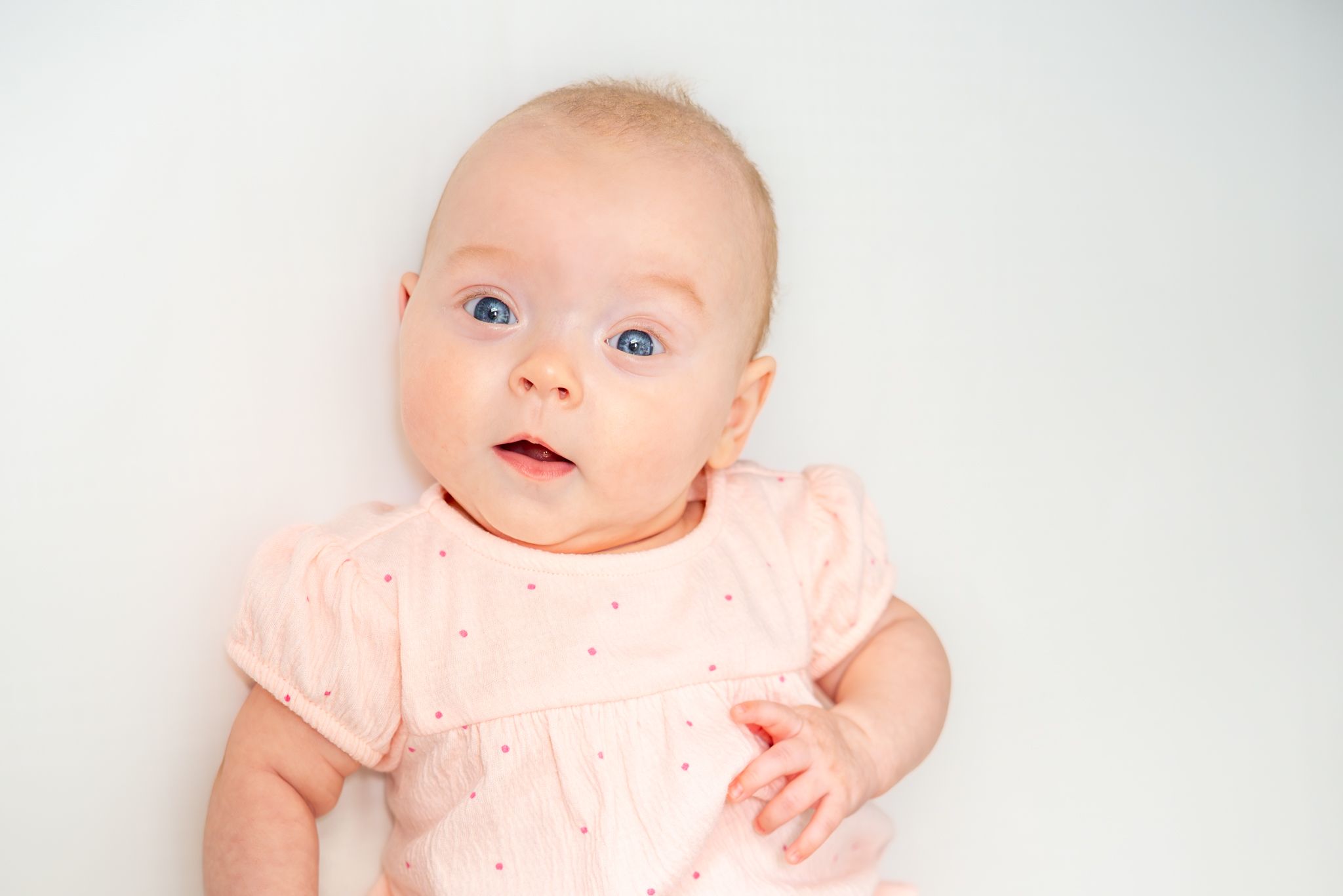 An infant with bright blue eyes against a light background. Quad Cities Newborn Photograph