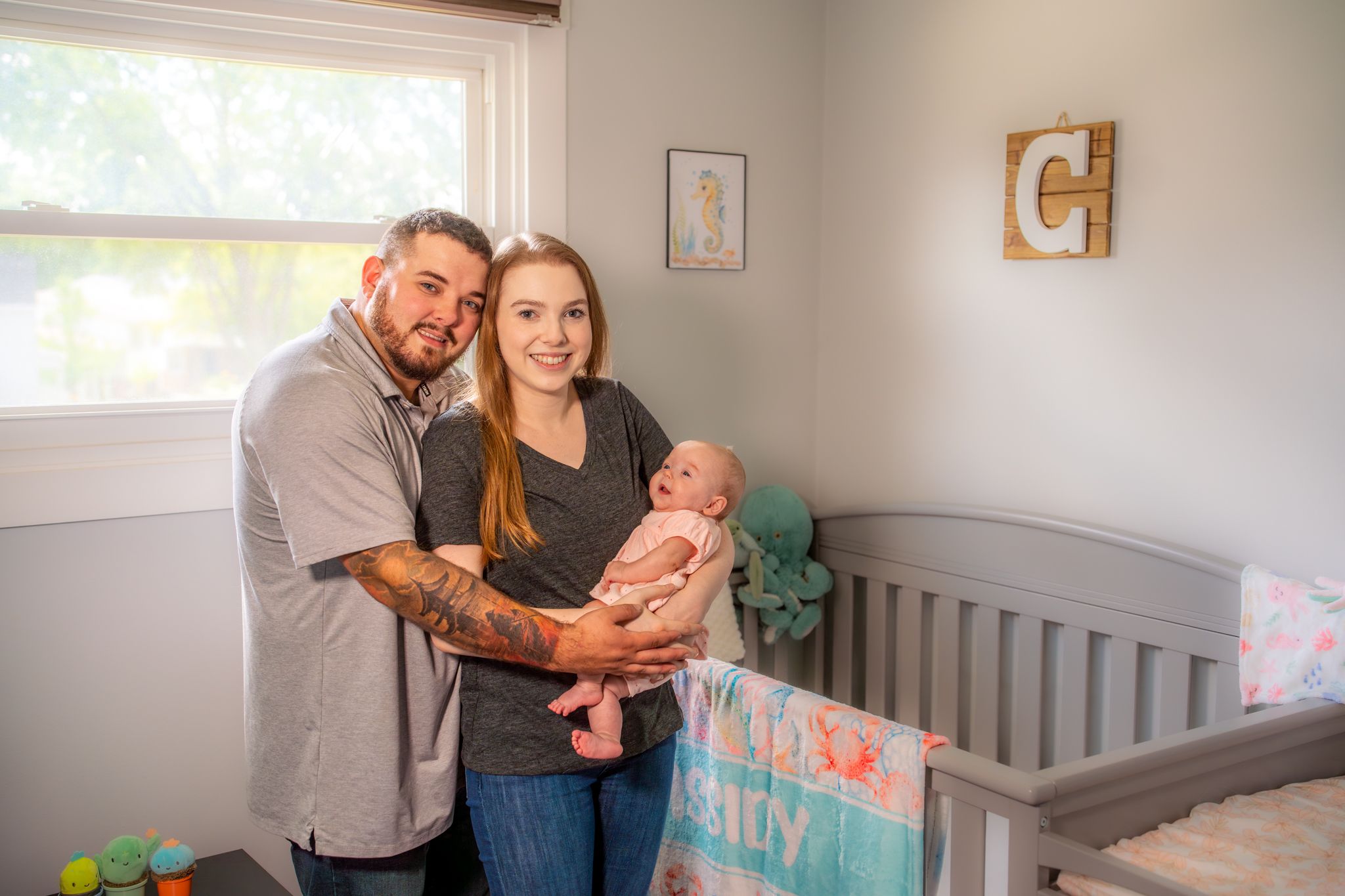 parents with their infant child in a nursery. Quad Cities Newborn Photography