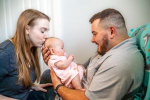 New parents sharing tender moments with their small infant while sitting together. Quad Cities Newborn Photography