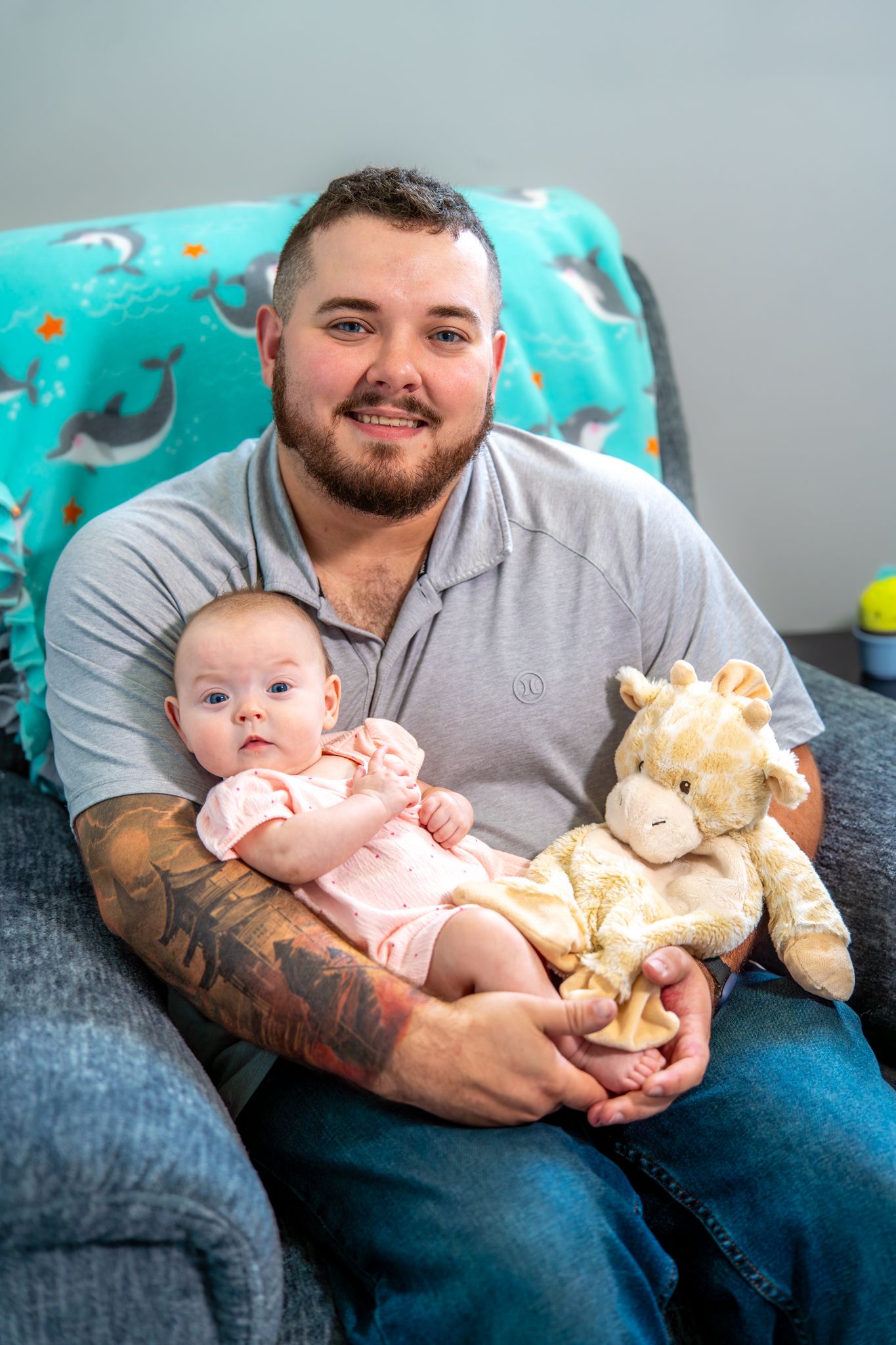 Series of tender moments shared between a parent and infant on a blue couch with a plush teddy bear. Quad Cities Newborn Photography