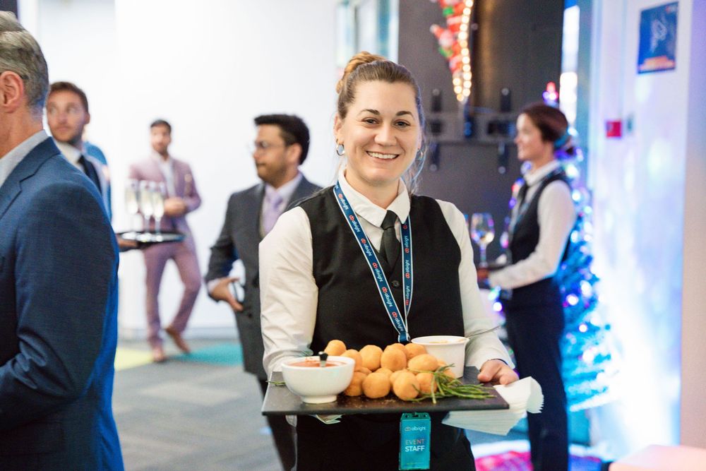 Group of professionals networking and enjoying refreshments at a corporate event with blue lighting and modern decor.