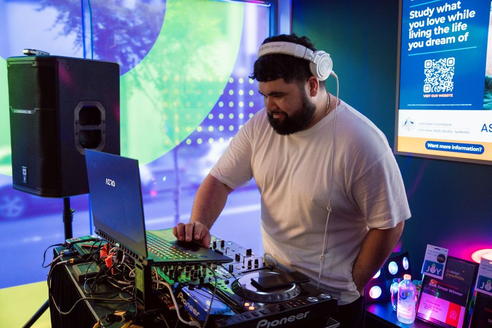 DJ setup with colorful blue and green lighting at a tech event showing mixing equipment and displays.