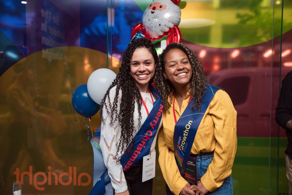 Holiday party attendees posing and smiling together in a festive venue with colorful lighting.