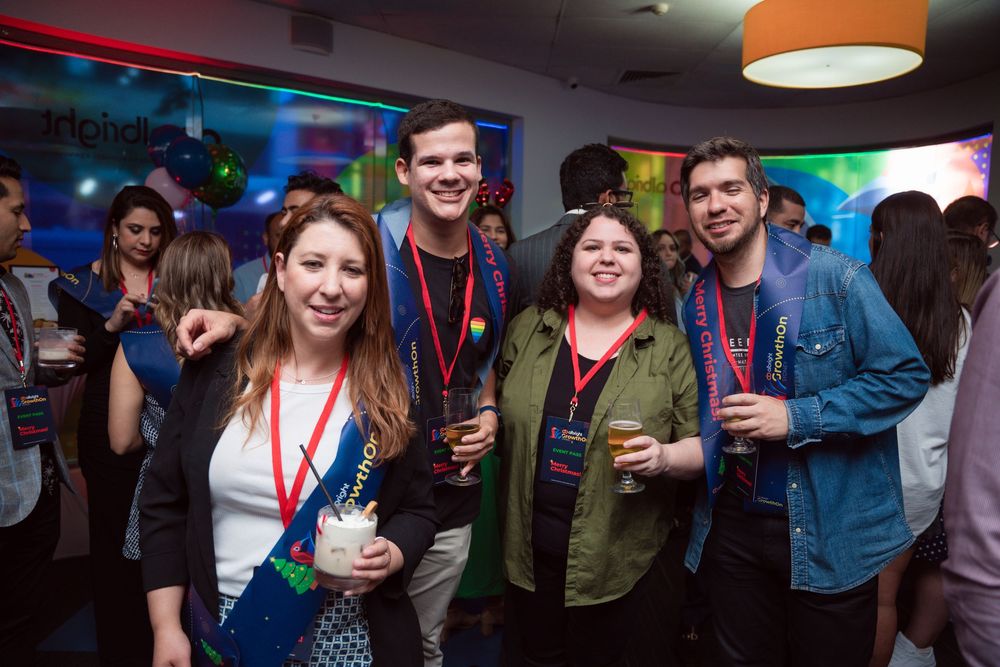 Attendees socializing and enjoying drinks at a corporate party with colorful lighting.