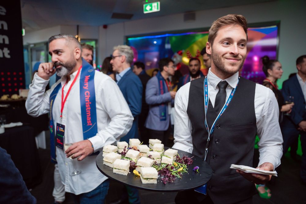 Professional event attendees socializing at a corporate party with drinks and appetizers.