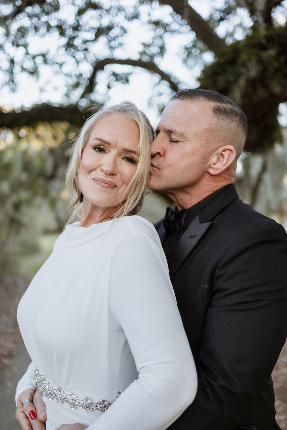 A romantic wedding couple shares tender kisses in a series of intimate portraits wearing white and black formal attire.
