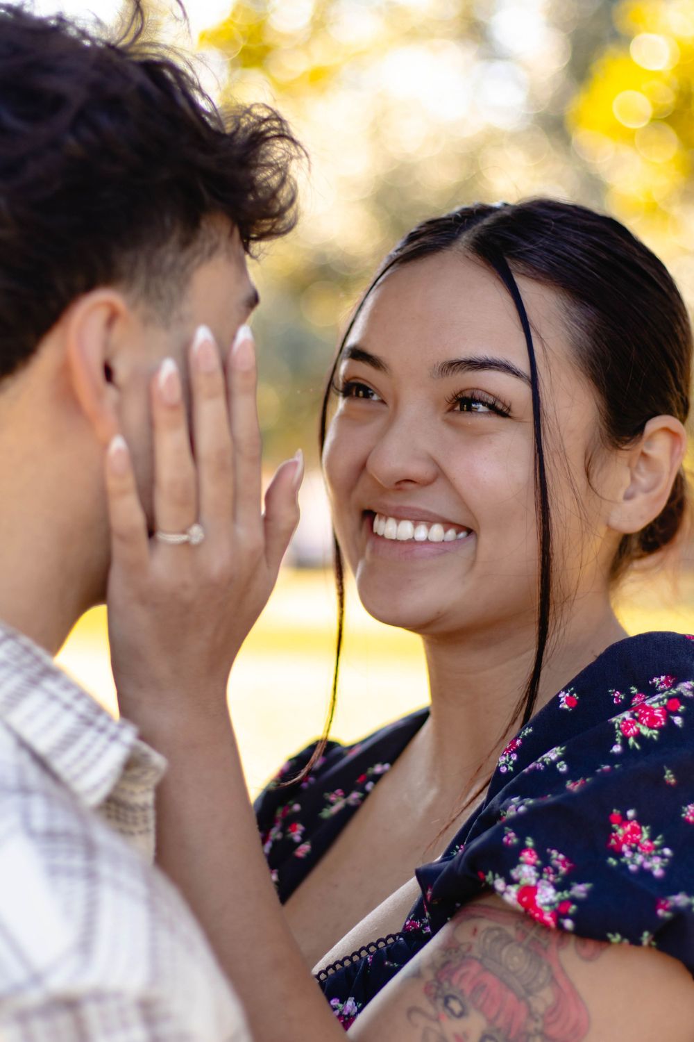 Close up of a couple sharing an intimate moment outdoors with autumn foliage in the background.