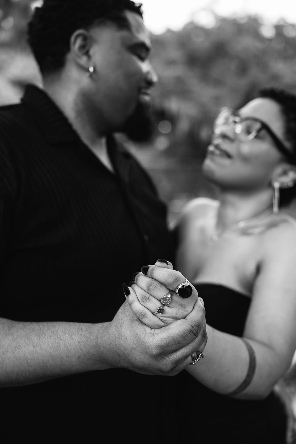 Black and white detail shot of hands holding and showing engagement ring.