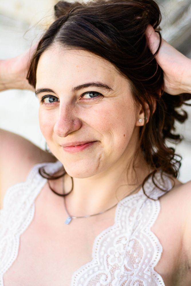 Natural light closeup portrait with soft smile against rustic background.