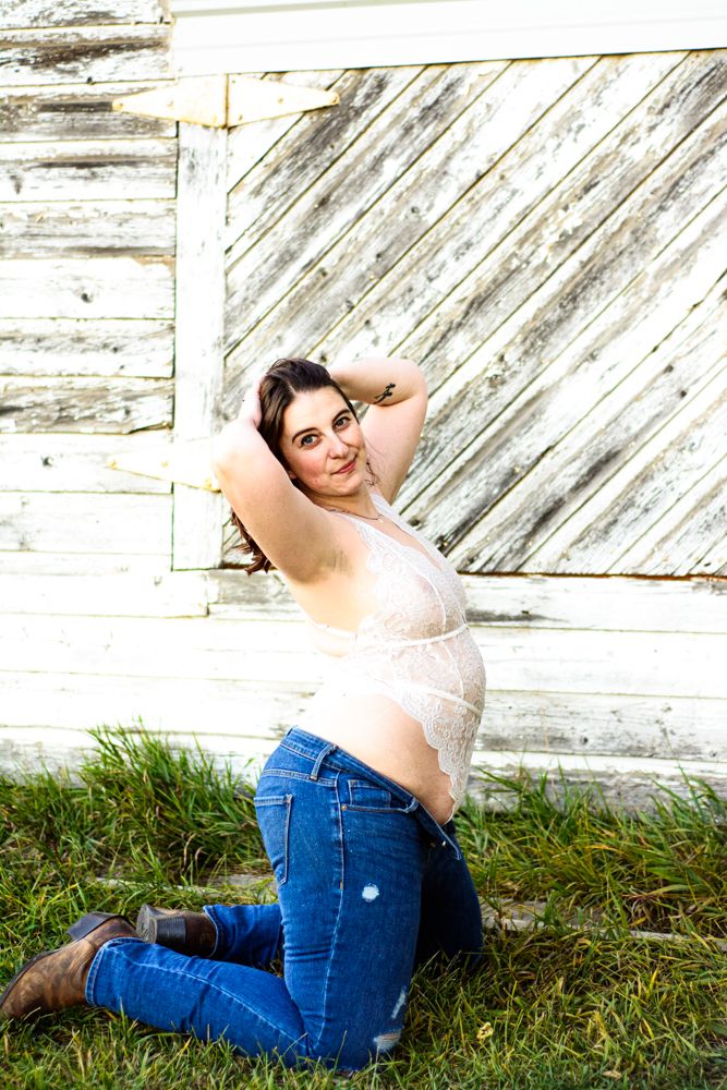 Casual outdoor portrait wearing lace top and jeans while posed against white wooden wall.