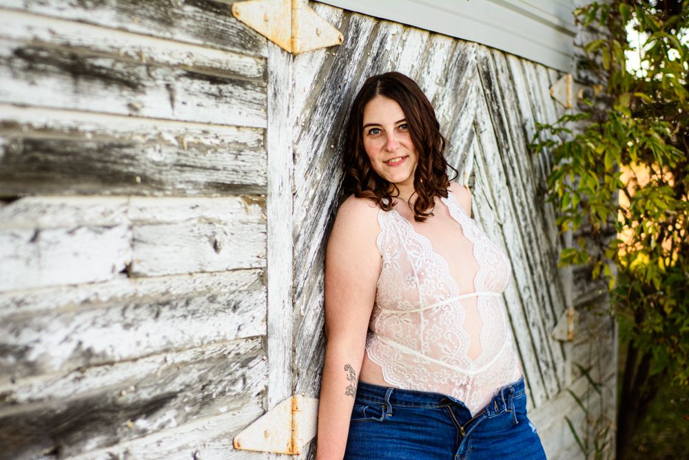 Natural light portrait against weathered barn wall in casual attire.