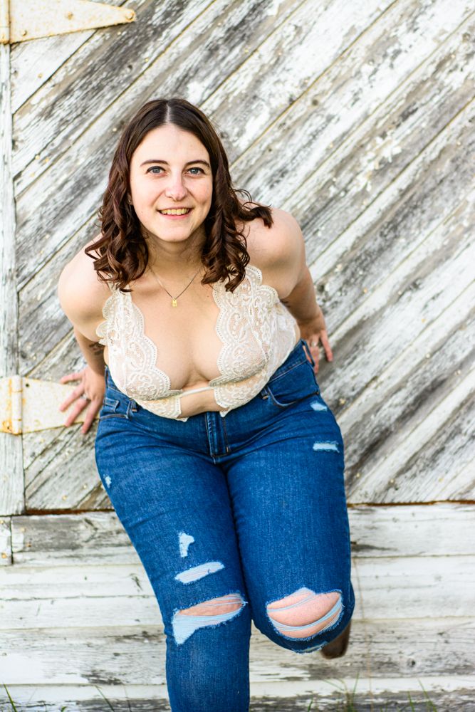 Casual portrait against weathered white wooden wall wearing lace top and distressed jeans.