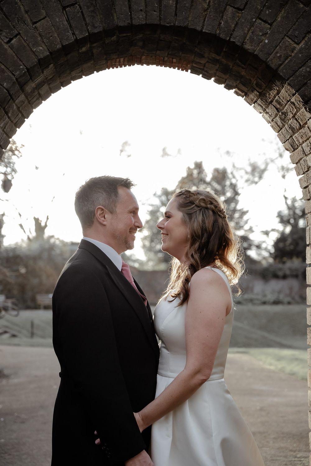 A romantic moment shared under a stone archway during a wedding photoshoot.