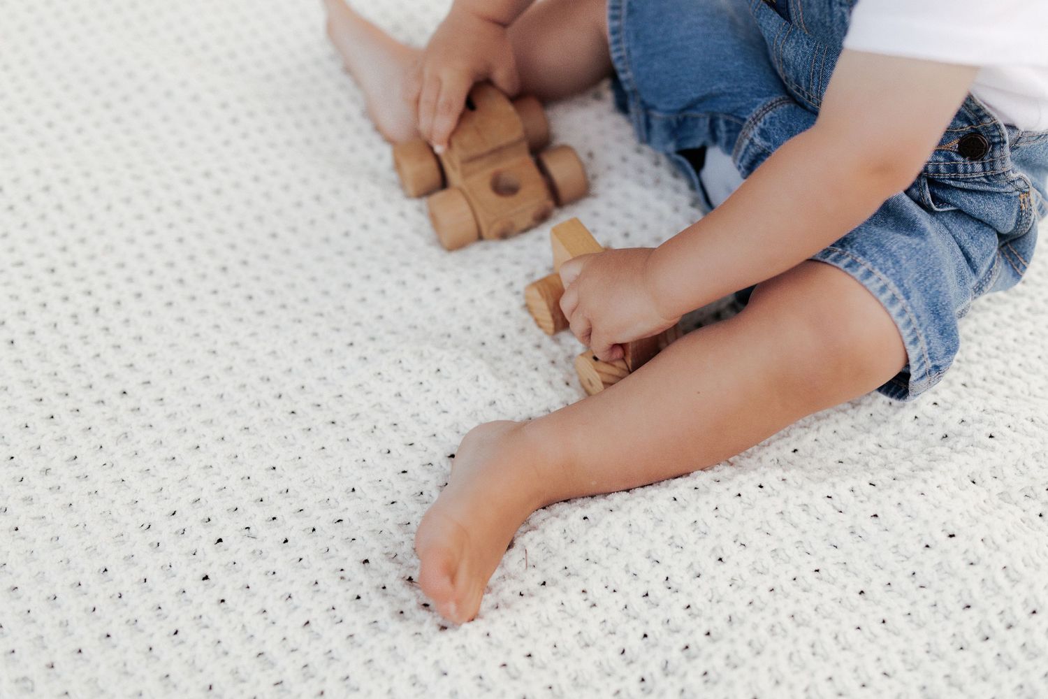 Little boy playing with toy trucks on blanket outside, Michigan