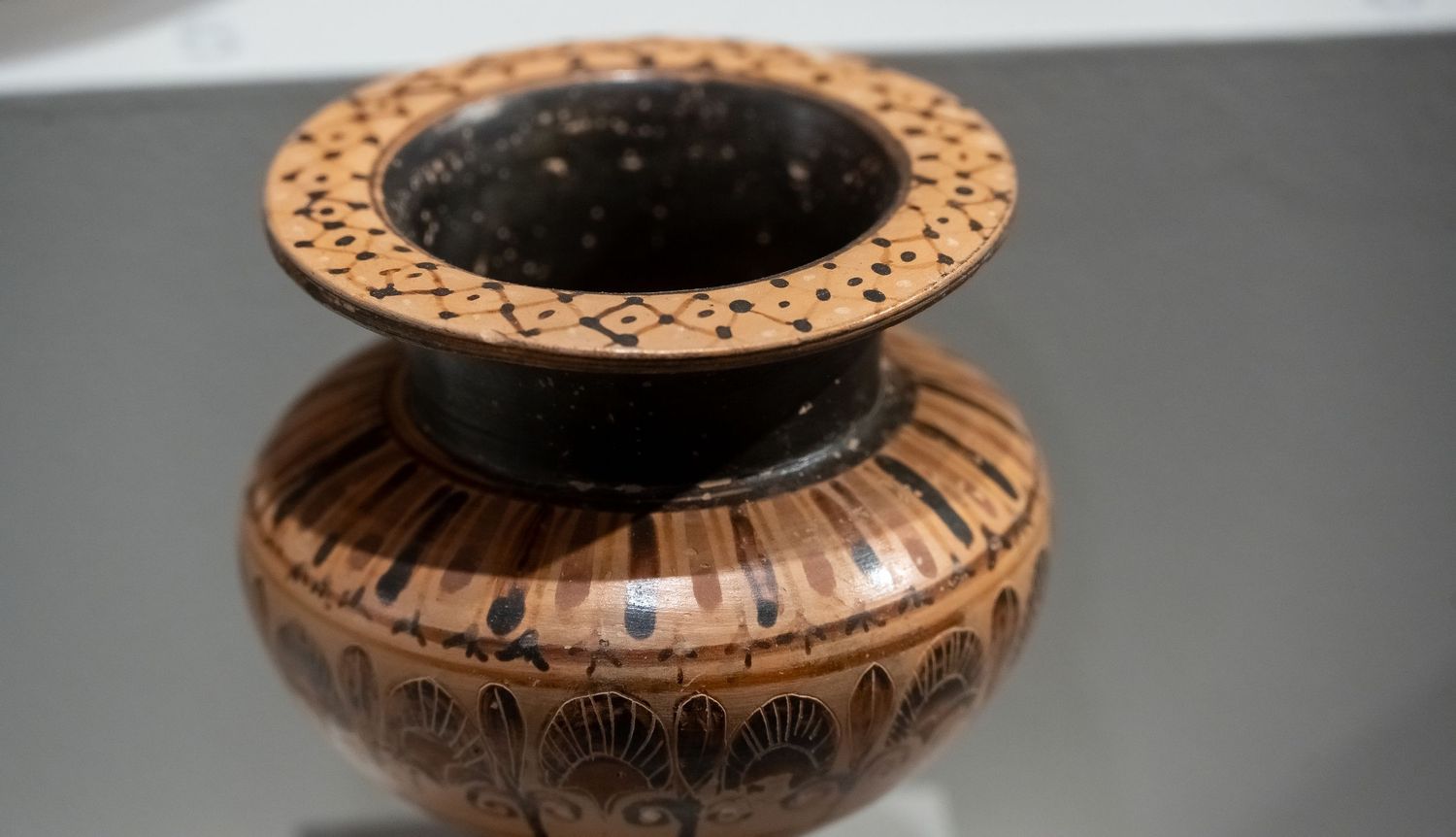 Decorative ancient pottery vessel with ornate patterns and shell designs around the rim.