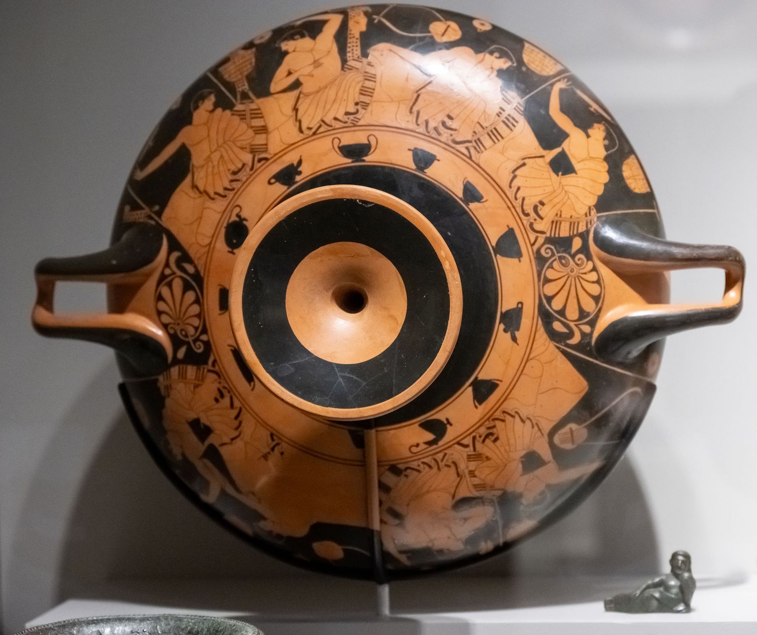 Top view of an ancient Greek pottery vessel with circular decorative patterns and handles.