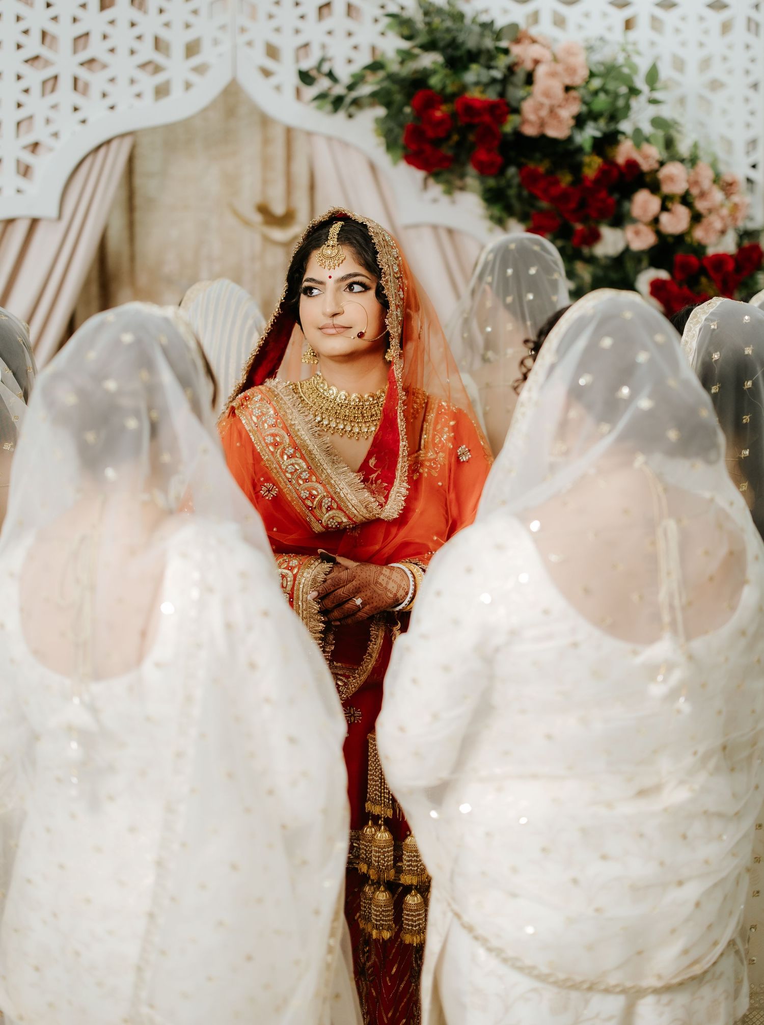 Traditional wedding ceremony with white-clad attendees and red floral decorations.