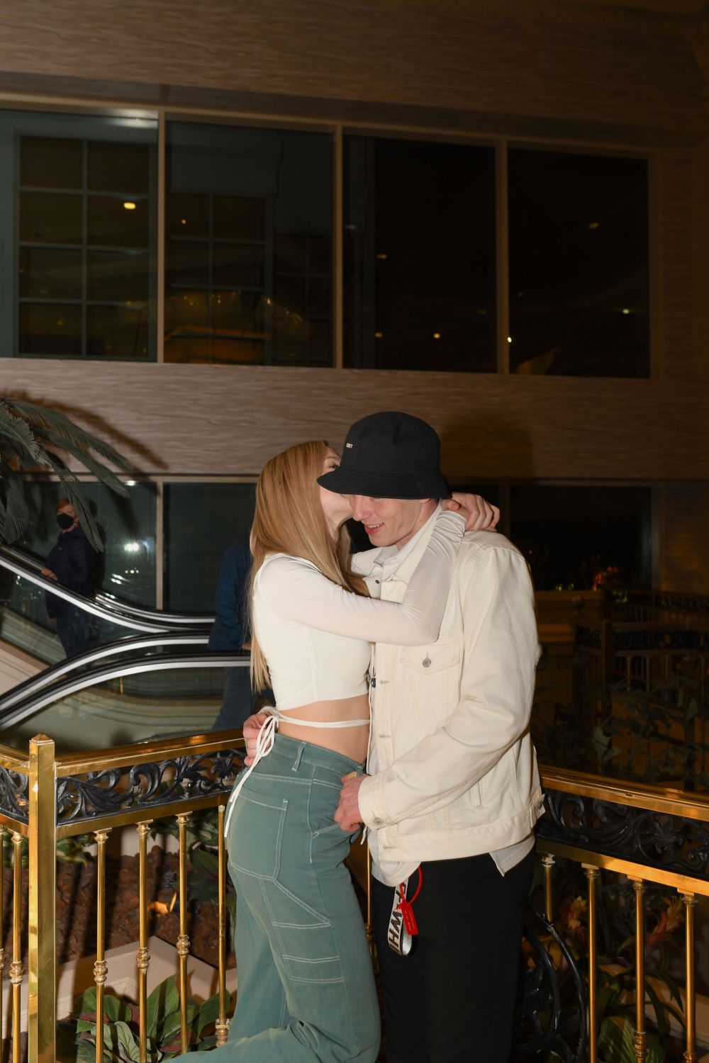 A romantic moment between a couple on a balcony with city lights in the background.