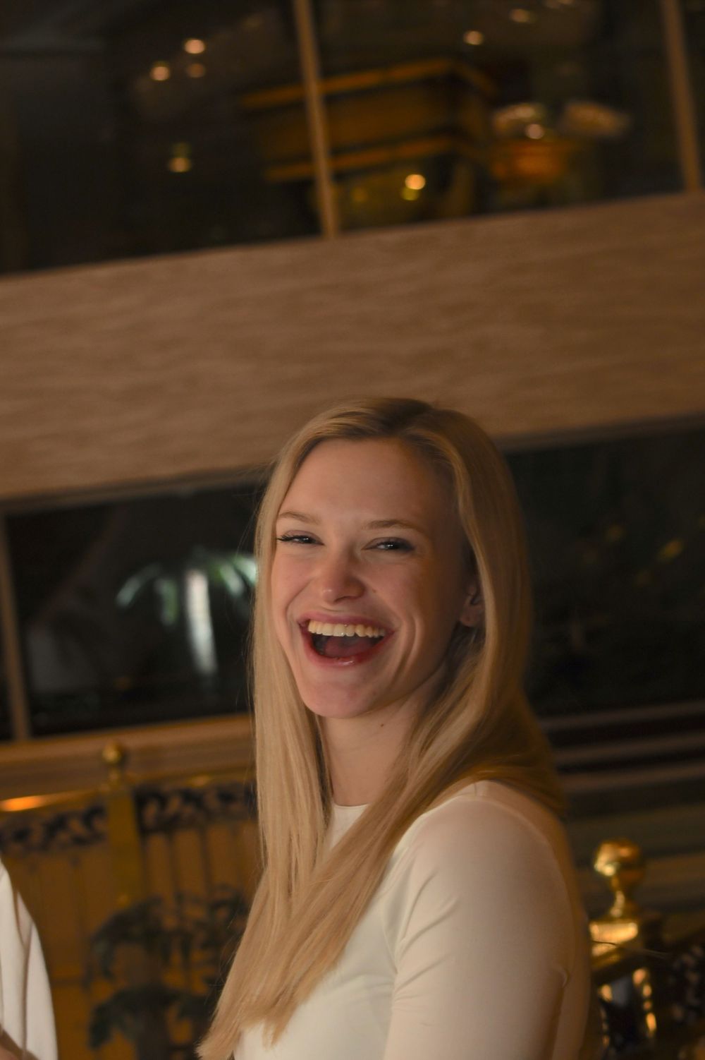 A candid portrait of a woman in white laughing joyfully.