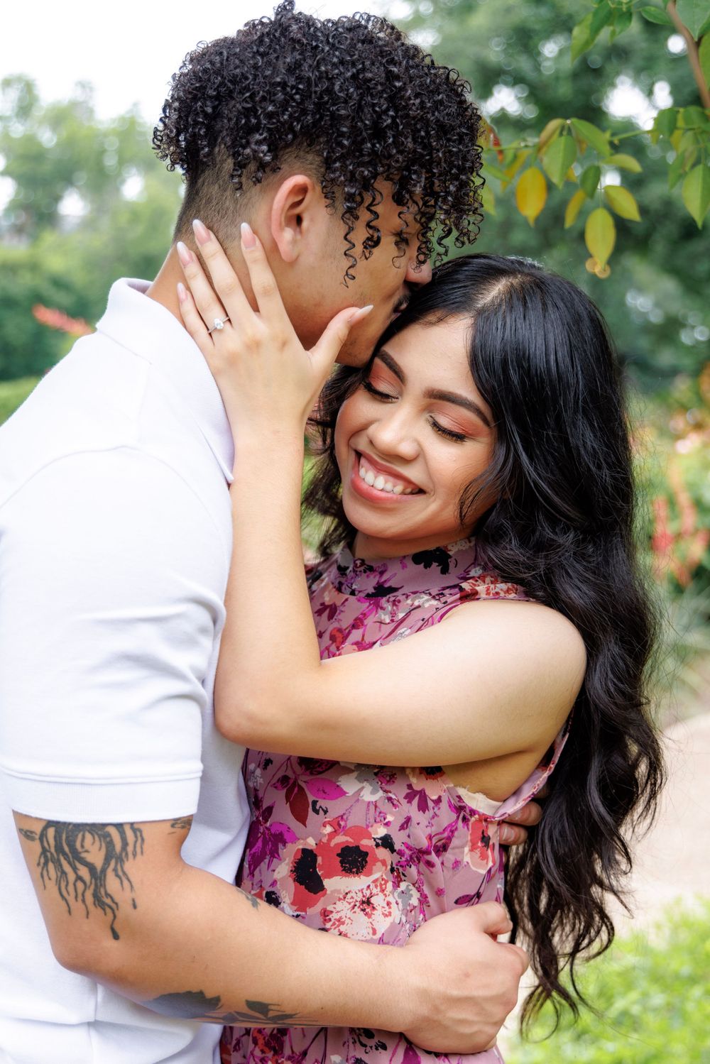 A tender embrace captured in a garden setting with blooming flowers.