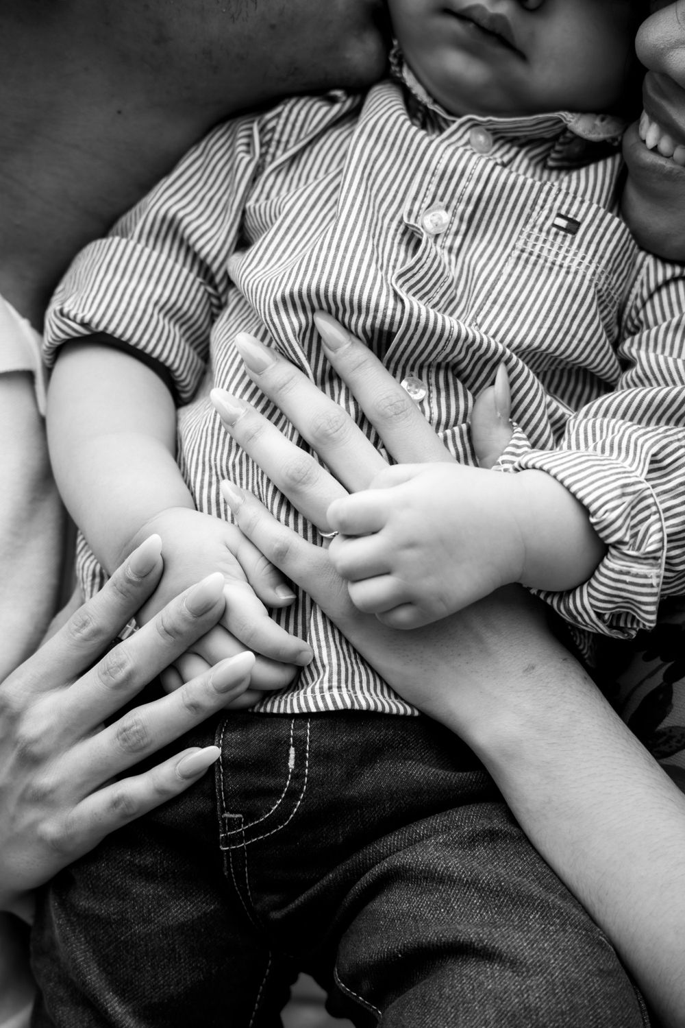 Black and white image of small hands touching and overlapping on striped clothing.