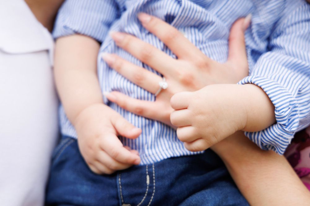Close-up of small child's hands resting on striped clothing.