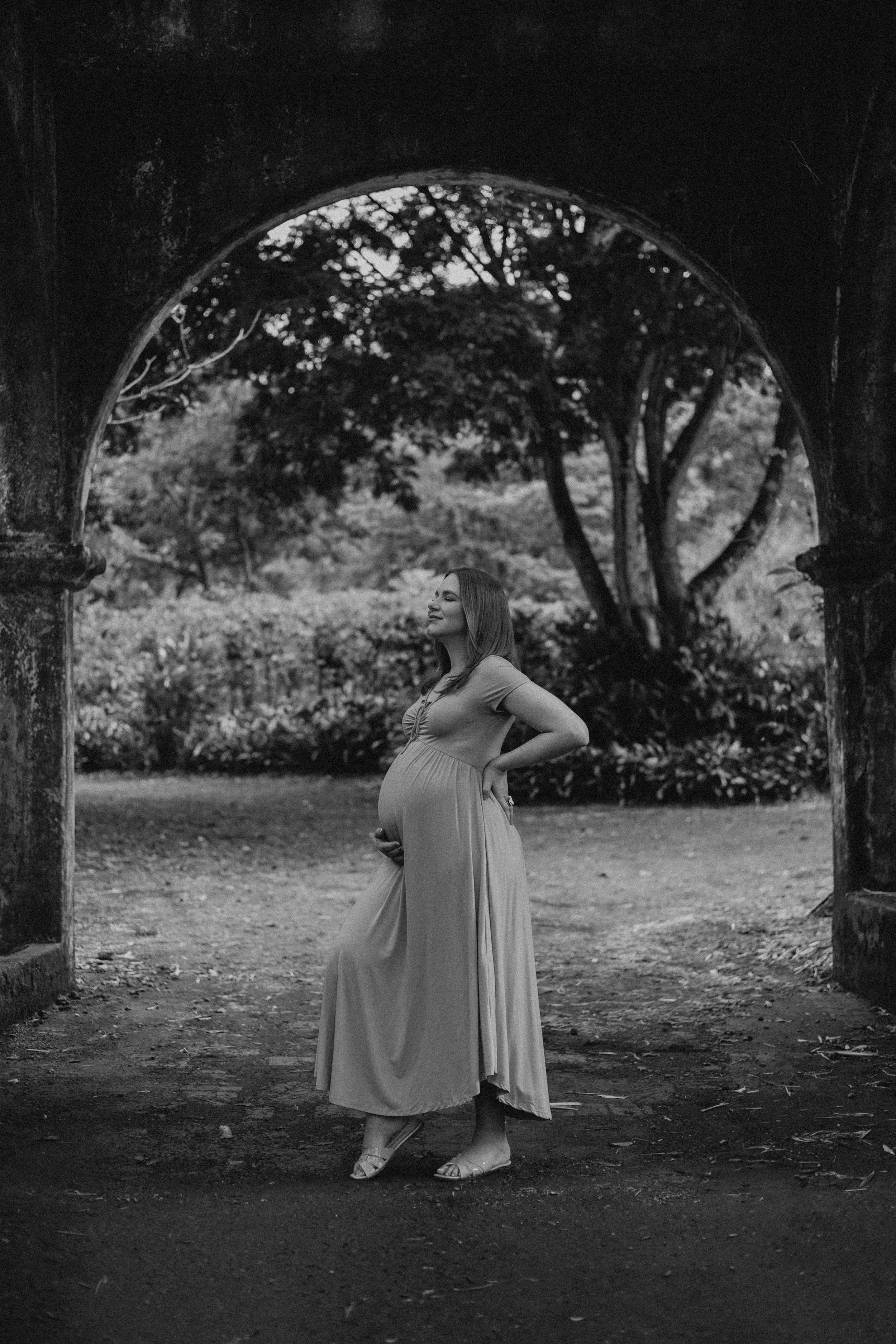 A sequence of black and white photos showing a person in a flowing dress crouching and posing in a garden setting.