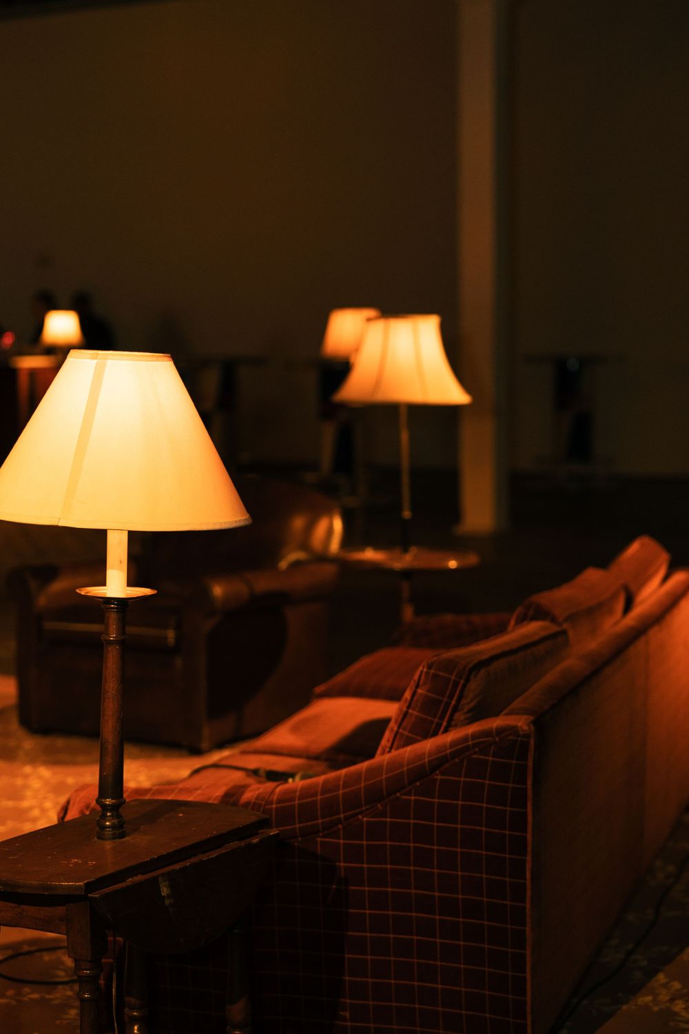 Warm table lamps cast a cozy glow over plush furniture in a dimly lit living room setting.