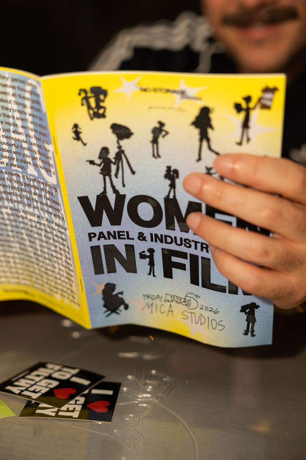 Close-up shots of yellow printed materials showing text and silhouette illustrations on a dark surface.