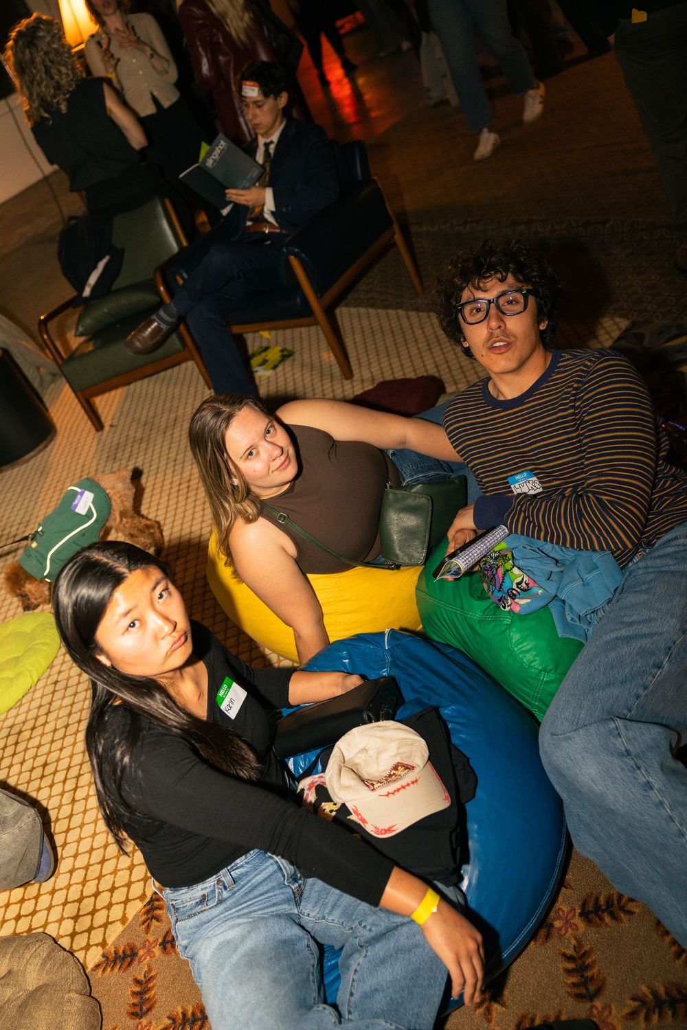 Group of young people lounging casually on floor during informal gathering or event.