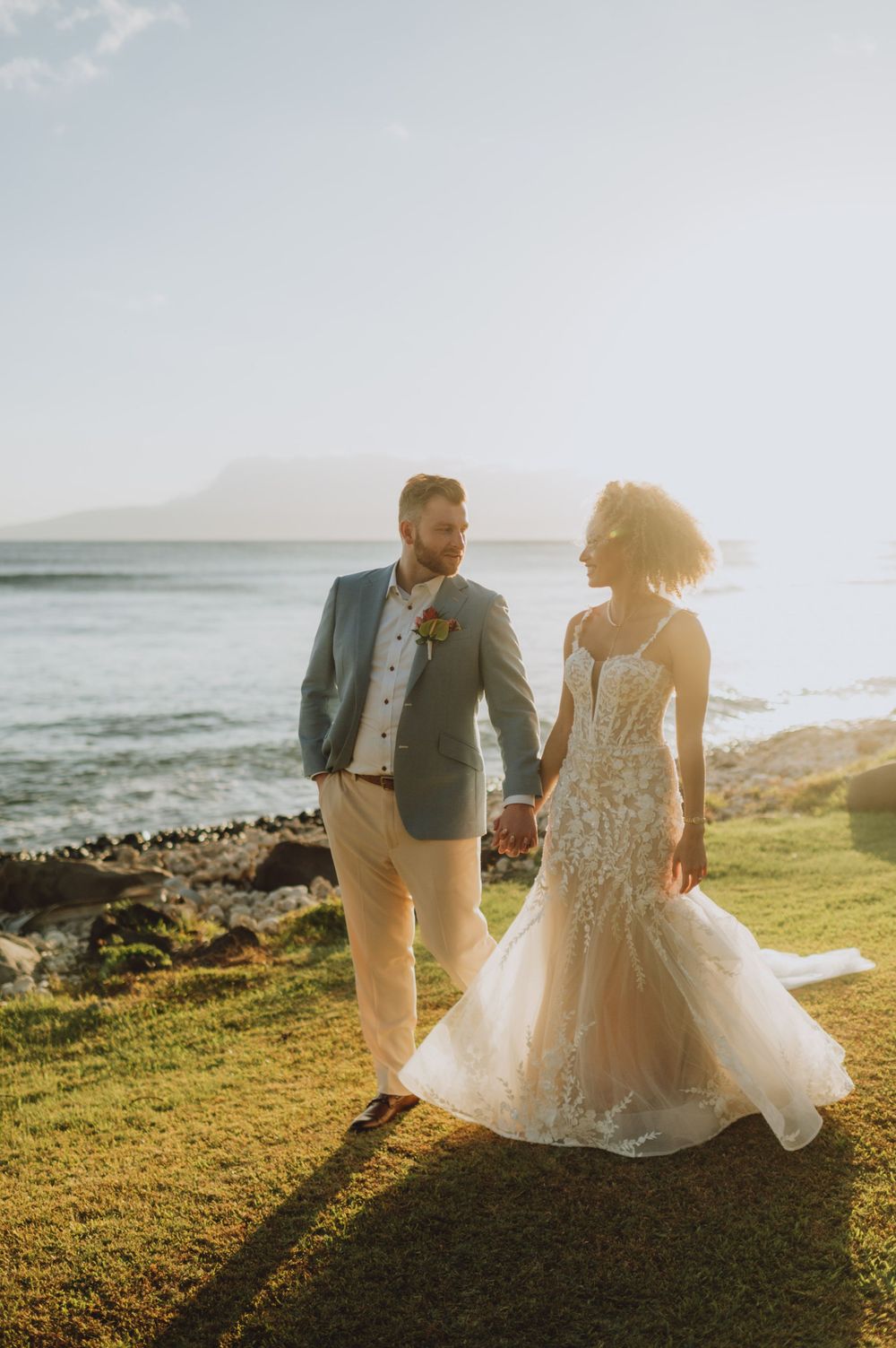 Romantic sunset wedding photos on grassy oceanside cliff in Hawaii.