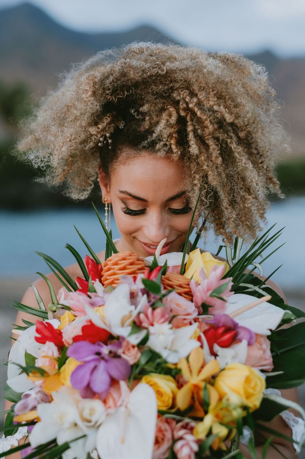 Colorful tropical wedding bouquet with lilies, roses and orchids against ocean view.