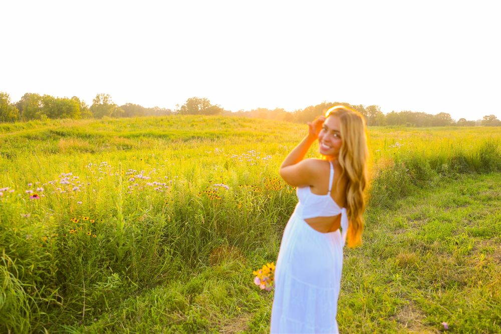 Golden hour senior session in a flower field with amazing golden light and a white dress holding flowers in Lake Elmo, MN.