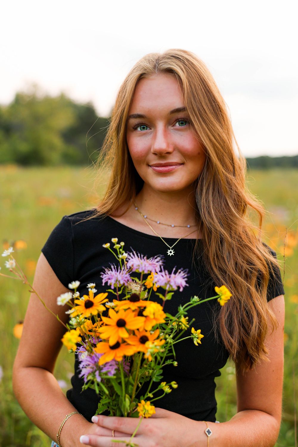 Senior photos with flower bouquet in a field.