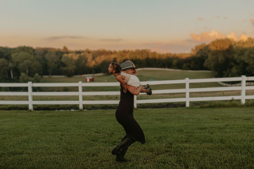 A panoramic view of a rural farm field at sunset with white fencing stretching across the landscape.