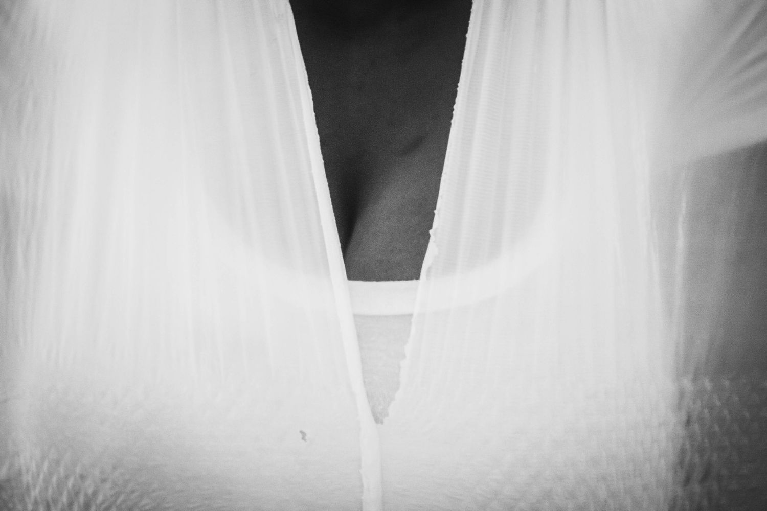 Close-up black and white detail of a wedding dress neckline showing delicate white fabric and plunging V-shape design.